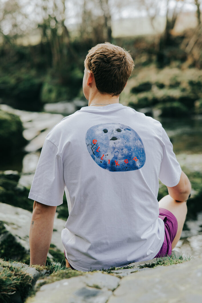Harry sitting by river in ELLIKER Rock Tee